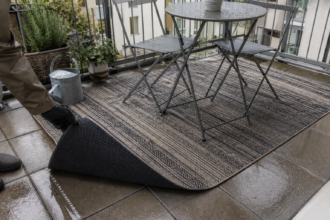 Wetterfester Outdoor-Teppich mit rutschfester Unterlage auf einem Balkon nach einem Regenschauer
